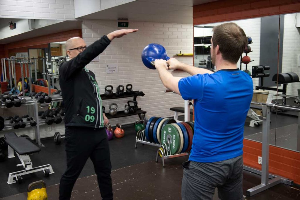 Man using a kettlebell for exercise with a trainer